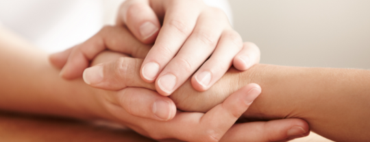 Female hand holding another female's hand to show support and caring