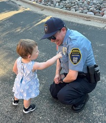 An Eden Prairie reserve officer kneels to speak with a little girl