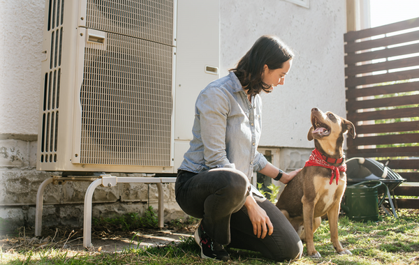 A woman and a dog in front of an electrical appliance