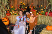 Three kids in costume taking a picture at a fall-themed selfie station