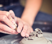 Close-up of a set of hands sculpting clay on a wheel