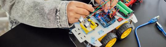 Engineering image of a kid's hands tinkering with a car