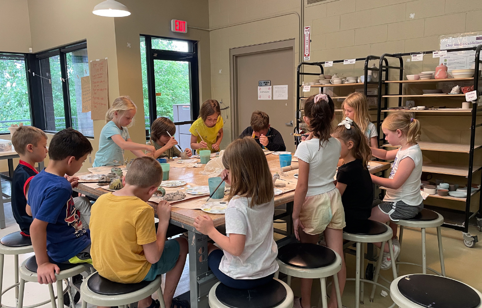 Group of kids seated around a table at the Art Center while working on an art project