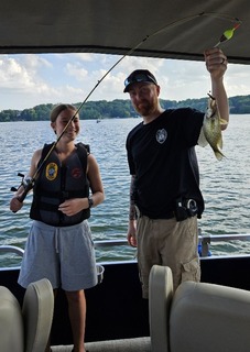A participant holds a fish with an officer