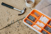 Close-up of hammer, roll of masking tape, nails and screws