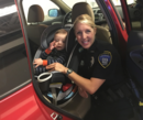 Police officer posing with a baby in a car seat