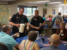 Two Eden Prairie police officers serving lemonade to dinner guests