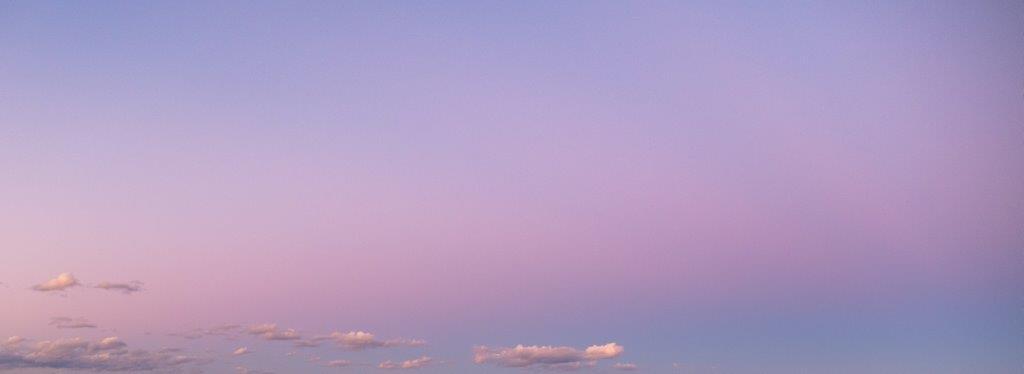 Pink and blue sky with sparse clouds at sunrise or sunset 