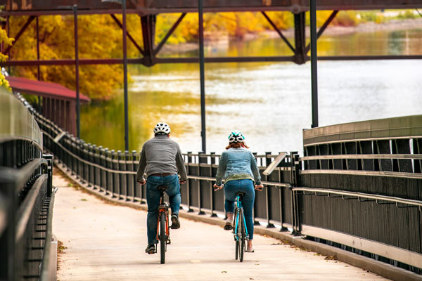 fall colors burst as a man and woman bike along a lake
