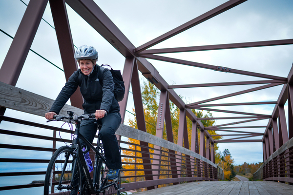 Woman biking over a bridge on the Gitchi-Gami State Trail
