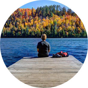 Woman sitting on dock, looking at fall colors