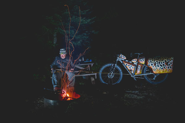man sits by a campfire at night