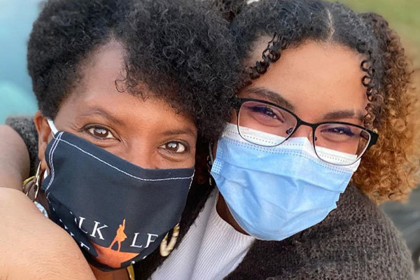 Healthcare worker wearing a mask makes a heart with her hands