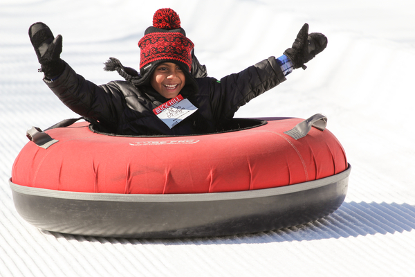 Smiling child snow tubing with his arms outstretched