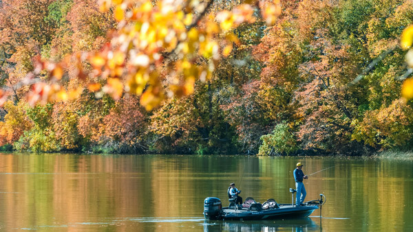 an image of a father and son fishing on a lake surrounded by fall color