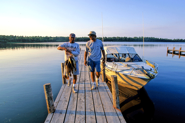 an image of two anglers on a dock with a large stringer of fish