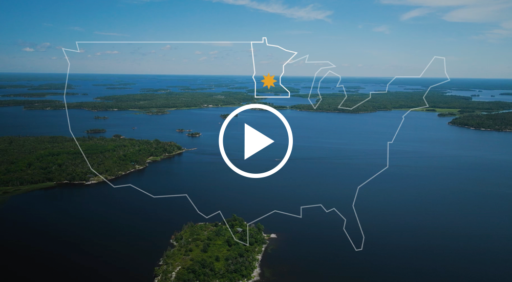 Screenshot from Explore Minnesota Film sizzle reel of lake landscape photo with an outline of the United States overlayed with MN starred