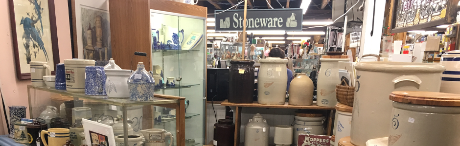 Shelves full of handmade pottery and other antiques fill a warm lit store.