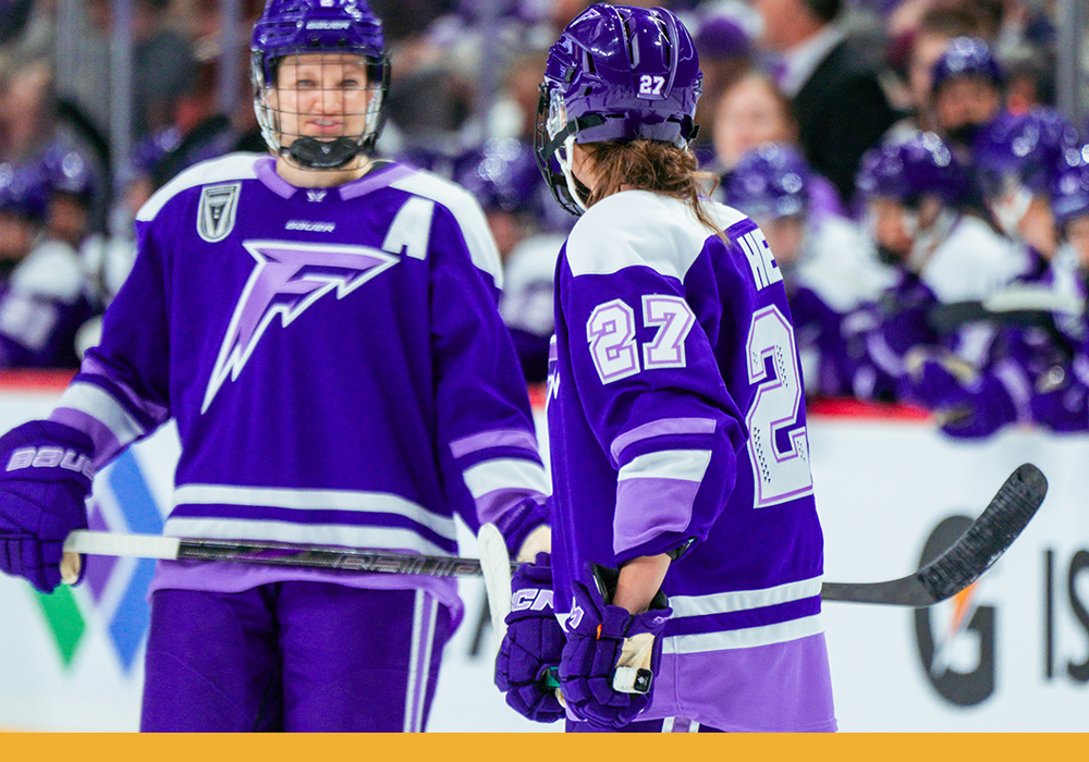 Taylor turned away from the camera, talking to a teammate on the ice in between plays during a Frost game.