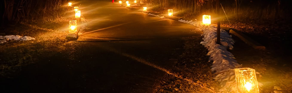 square ice luminaries radiate yellow light, illuminating a paved sidewalk.