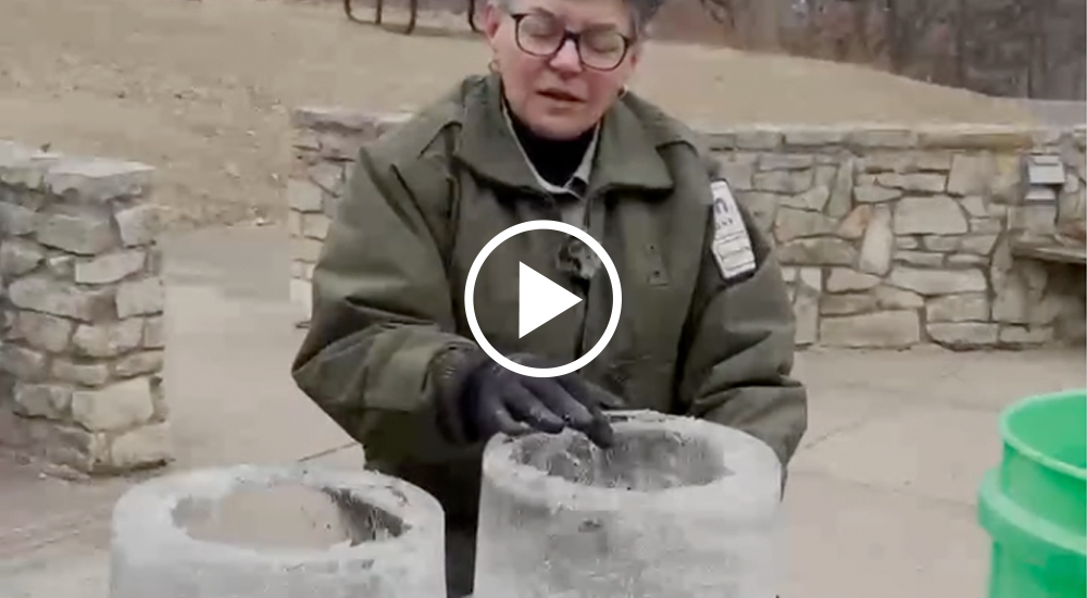 Video still: person outside shows the thickness of an ice luminary, a green bucket can be seen slightly off camera.