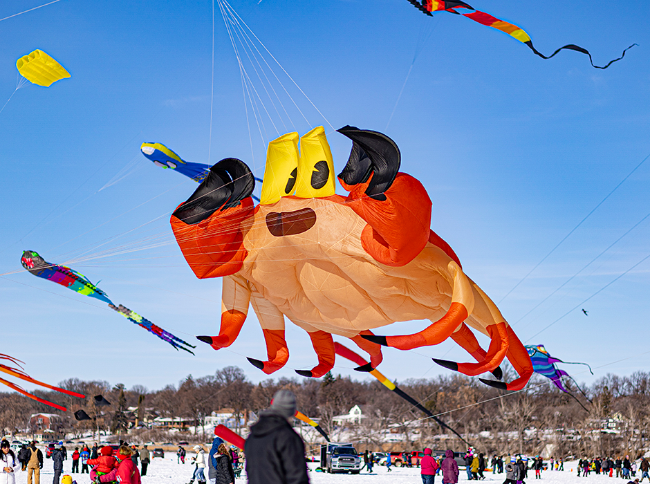 a giant crab kite soars above a crowd on the white, gleaming ice