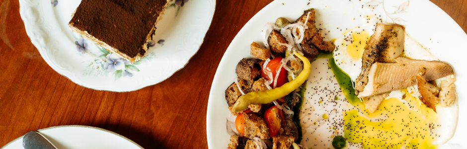 an overhead shot of a beautiful egg and hash brunch with a side of tiramasu, both on fine china.