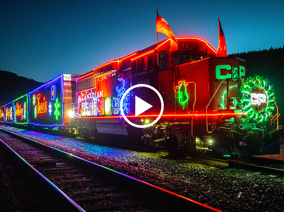 A Canadian Pacific train is decorated it moving and colorful lights. Snowflakes, wreaths, and bells are amongst the lighted subjects.