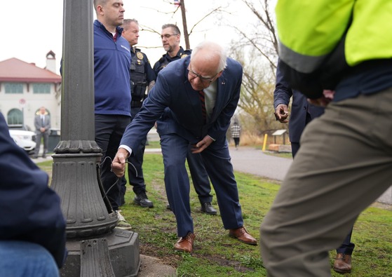 Governor Walz looks at streetlamp with copper wire damage 