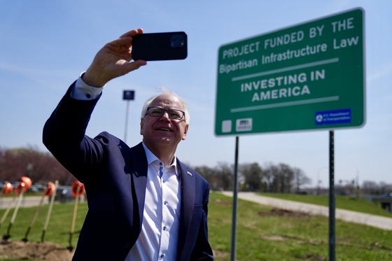 Governor Walz takes a selfie with a sign off of I-90 in Austin noting that the future project will be funded by the Bipartisan Infrastructure Law