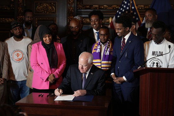 Governor Walz signs ride share bill into law surrounded by legislators and community leaders