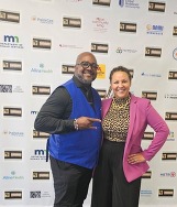 Corey and Ashley posing near event banner.