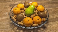 Photo of a bowl of pears, kiwis, oranges, and nuts in the shell
