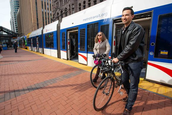 A man and woman getting off the Light Rail Transit train with their bikes in downtown Minneapolis