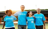 Photo of people standing side by side with arms linked, wearing t shirts that say Volunteer on them