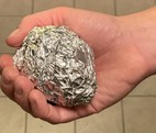 Hand holding ball of aluminum foil for recycling