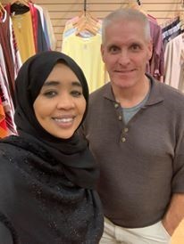 Photo of a woman wearing a hijab standing with a man and smiling for the photo
