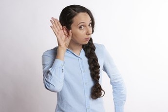 Photo of a woman cupping her hand to her ear to hear better