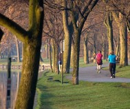 Photo of adults running or walking on a path by a lake in the spring 
