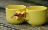 Photo of two yellow mugs linked together by the handles with a piece of twine
