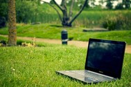Photo of an open laptop computer sitting outside on green grass