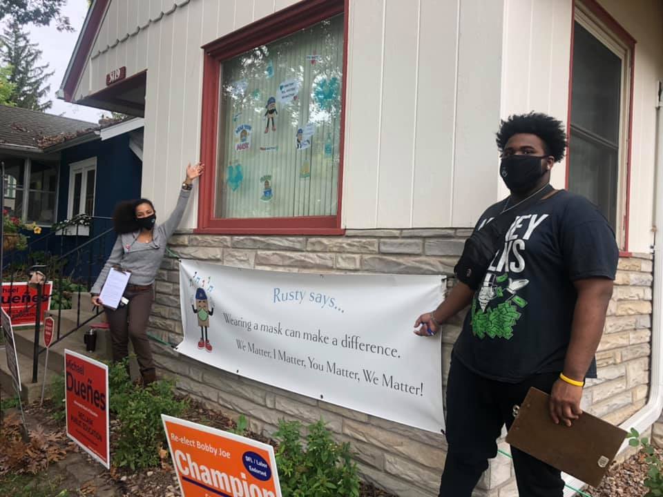 Person standing outside with banner at Litter Be Gone cleanup