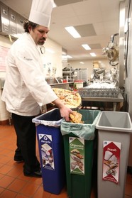 Chef putting leftover pizza into clearly labeled organics recycling bin