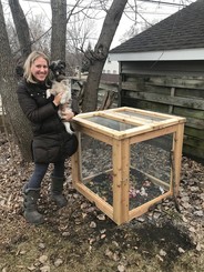 Woman holding dog standing next to Hennepin County compost bin
