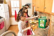 Girl in kitchen putting food scraps into organics recycling container