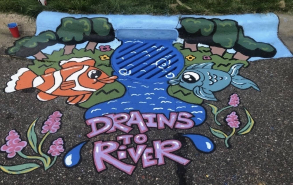 Painting on a storm drain indicating that the drain goes to the river