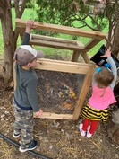 Two kids putting materials into a compost bin