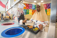 Girl putting milk carton into recycling bin in school cafeteria