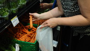 Woman putting carrot into reusable produce bag