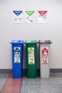 Trash, recycling, and organics bins with detailed signs on each
